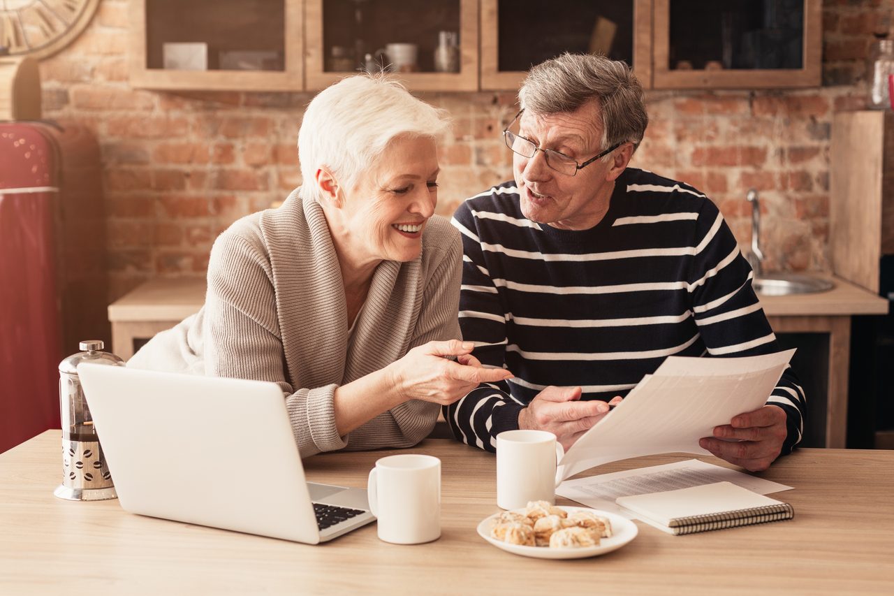 Senior couple reviewing retirement income documents together at their kitchen table