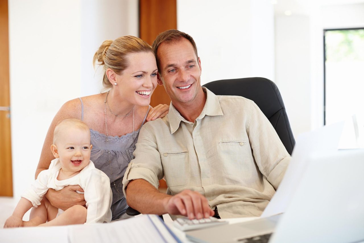 Young family smiling at their laptop while planning their financial future together with GFI USA