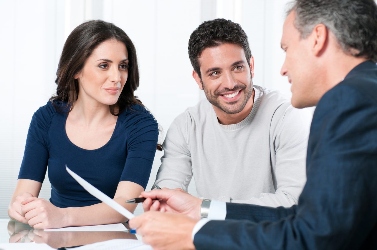 Financial advisor explaining a wealth strategy to a young couple during a consultation